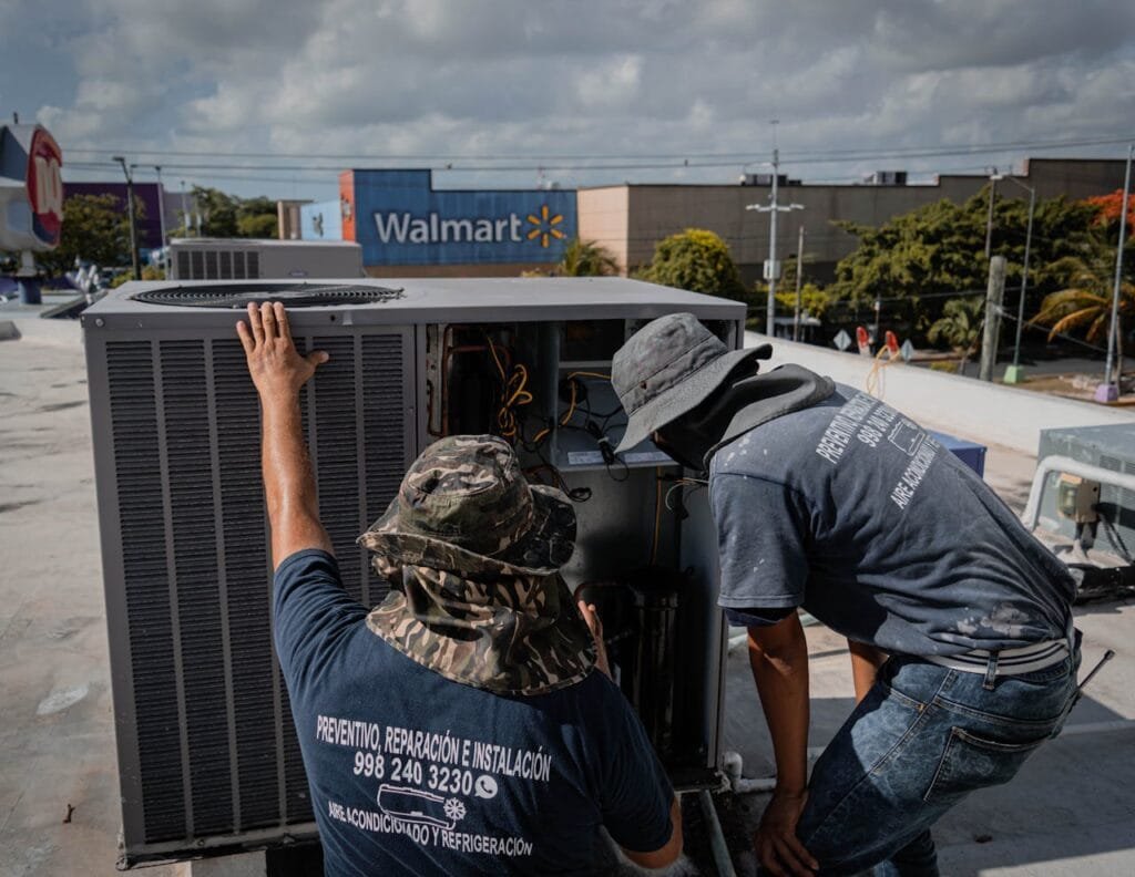 men wearing hats looking at the outside unit of an air conditioner at the rooftop 5463577.jpeg